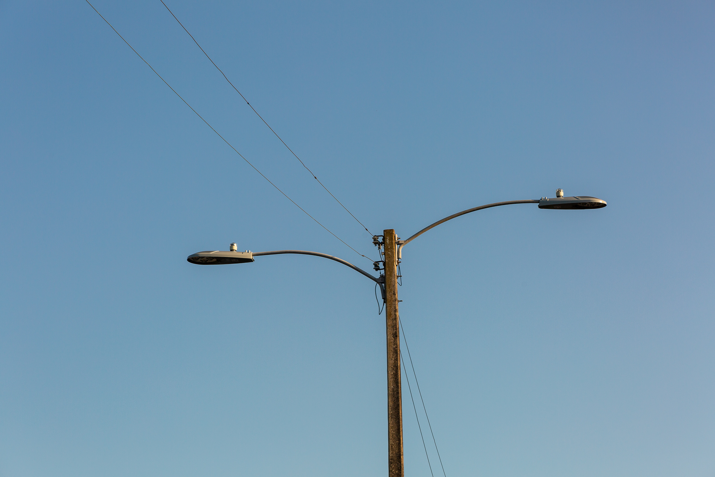 Twin-arm roadway light pole against a clear sky